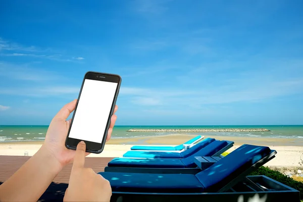 Smart phone in hand is sending a message, the back is the beach