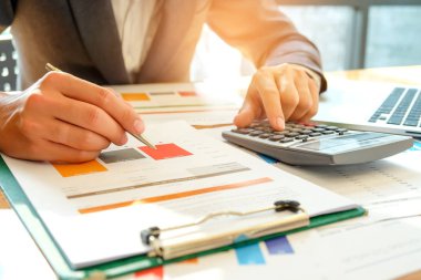 İşadamı grafik verileri analiz eder ve calcul için hesap makinesi kullanma