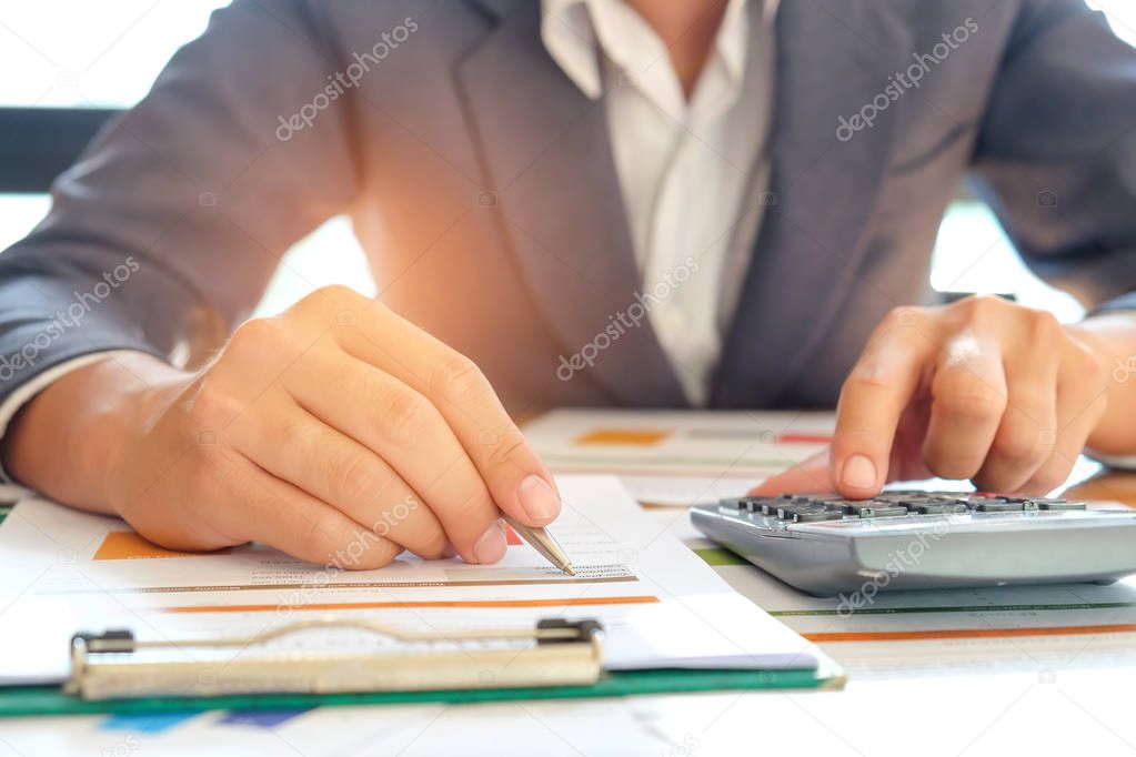 Businessman analyzes graph data and use the calculator to calcul