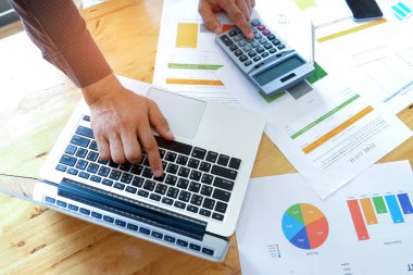 İşadamları belgelerle kullanarak dizüstü bilgisayarlar ve hesap makineleri ve