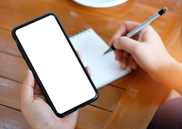 Smartphone in de hand van de vrouwen, andere hand houdt de pen schrijven op niet — Stockfoto