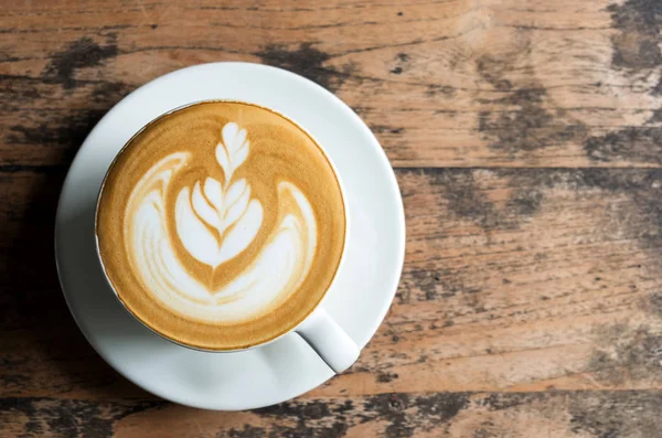 Latte yaprak makyaj ahşap zemin üzerinde beyaz Kupası.