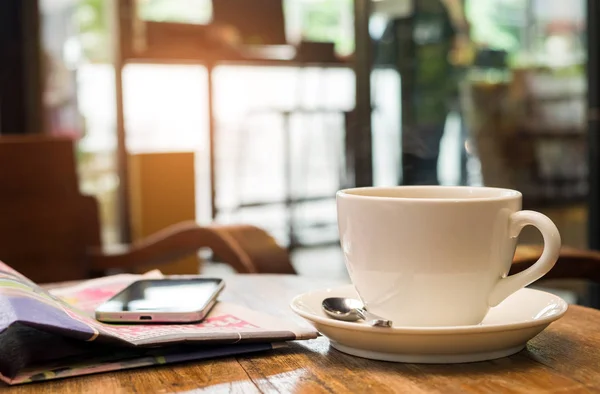 Kaffe och en smart telefon är på tidningen. — Stockfoto