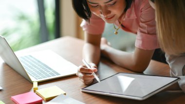 Ofiste birlikte çalışan Asyalı kadın grafik tasarımcısı. Laptop ve tablet kullanıyorlar..