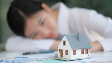 Emlak konsepti, arka planda kız olan ön model ev. Eve bak. Bir ev almayı hayal etmiş..