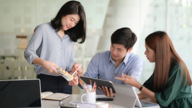 Modern ofis odasında dijital tablet kullanarak akıllı telefon uygulama projesi üzerinde çalışan genç tasarımcı ekibinin kırpılmış görüntüsü.