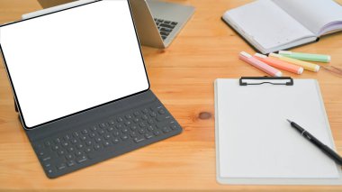 Dizüstü bilgisayarın, not defterinin ve ofis malzemelerinin kesilmiş görüntüsü ofisteki ahşap bir masada..