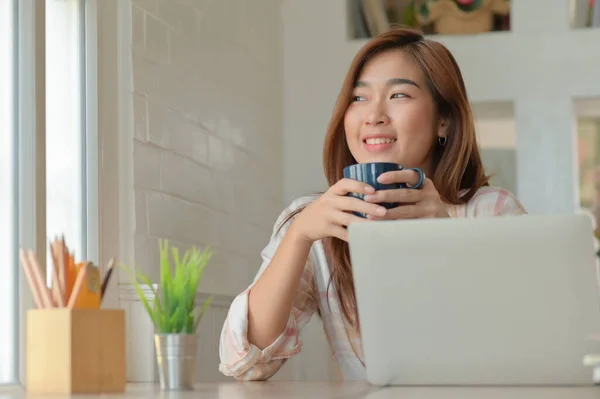 アジアの女性は快適なオフィスで働くことから休憩中にコーヒーカップで喜んで笑顔 — ストック写真