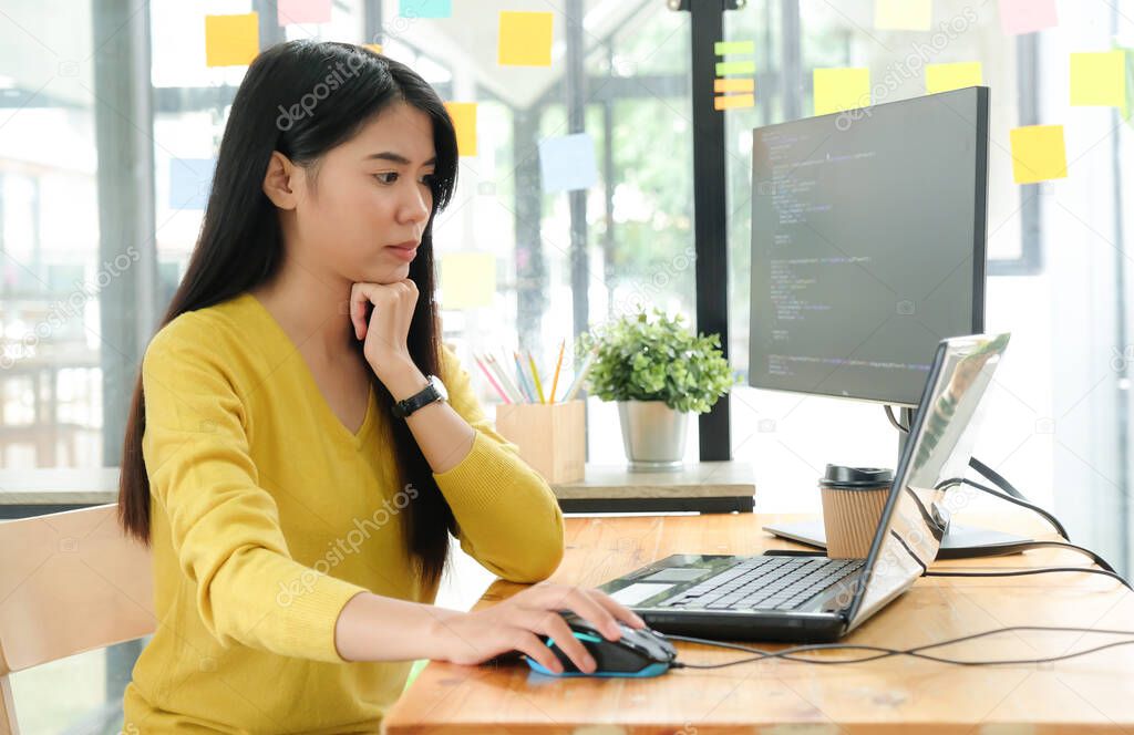 Female programmer are using laptop to create programs for clients.She put hand on the mouse and and face was serious.