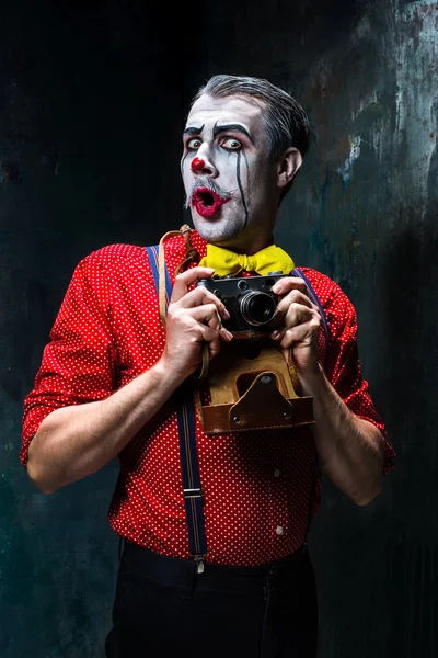 De enge clown en een camera op dack achtergrond. Halloween concept — Stockfoto