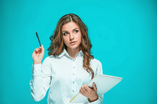 La joven empresaria reflexiva con lápiz y tableta para notas sobre fondo azul — Foto de Stock