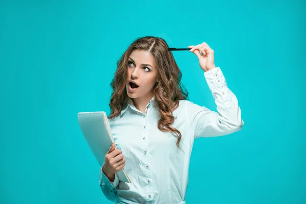 考虑周到的年轻商业女人的钢笔和平板电脑在蓝色背景上的笔记 — 图库照片