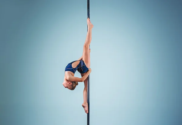 La joven fuerte y elegante que realiza ejercicios acrobáticos en el pilón — Foto de Stock