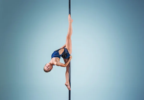 La jeune fille forte et gracieuse effectuant des exercices acrobatiques sur pylône — Photo