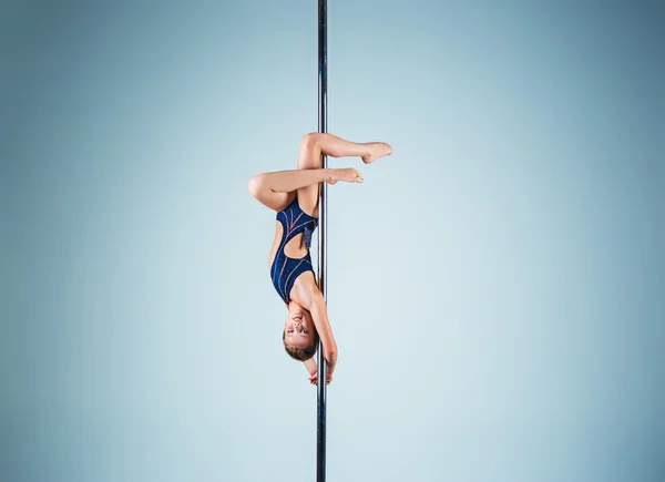 La jeune fille forte et gracieuse effectuant des exercices acrobatiques sur pylône — Photo