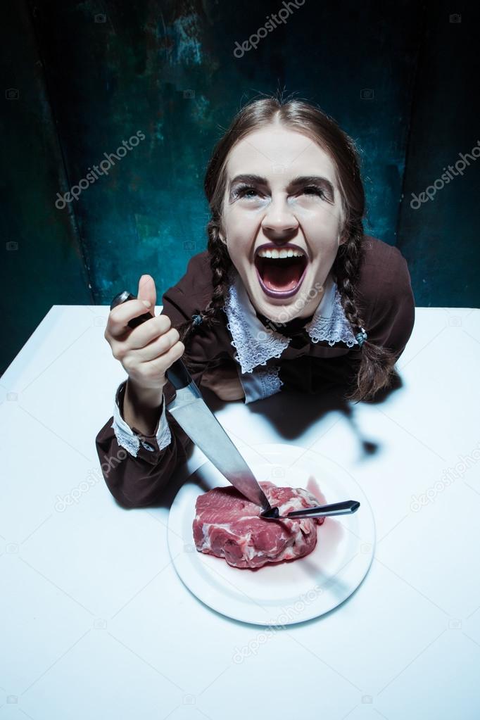 Bloody Halloween theme: crazy girl with a knife, fork and meat