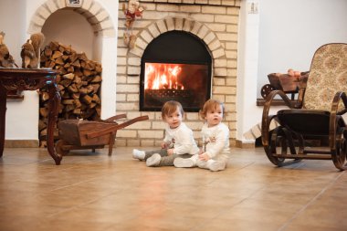 Evde şömineye karşı oturan iki küçük kız.