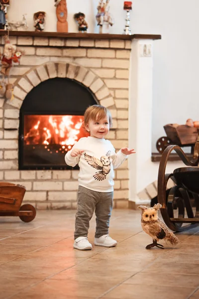 Šťastné dětské děvčátko stojící doma proti krbu — Stock fotografie