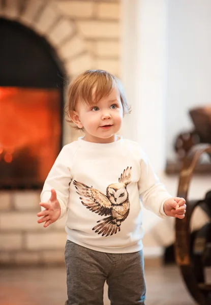 暖炉に対して家に立っている幸せな子供の小さな女の子 — ストック写真