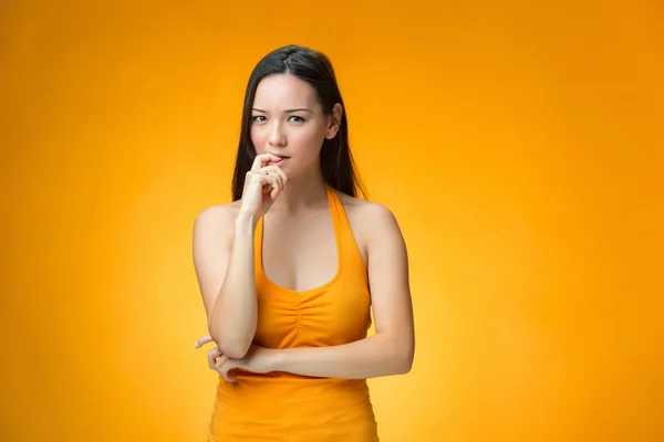 La chica china pensante sobre fondo amarillo —  Fotos de Stock