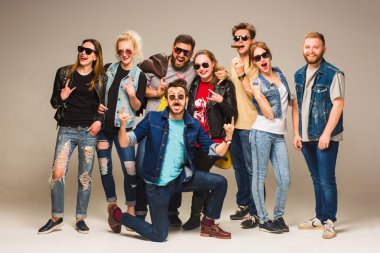 Mavi Jeans gri arka plan karşı kameraya gülümseyen mutlu genç arkadaş grubu.