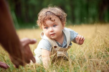 The little baby or year-old child on the grass in sunny summer day. clipart