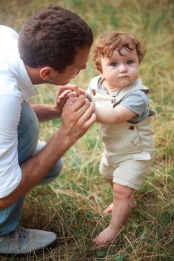 Genç güzel baba ve küçük yürümeye başlayan çocuk oğlu yeşil çim karşı