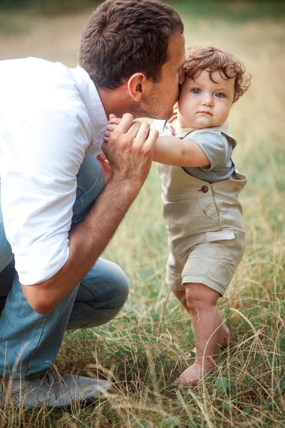 Genç güzel baba ve küçük yürümeye başlayan çocuk oğlu yeşil çim karşı