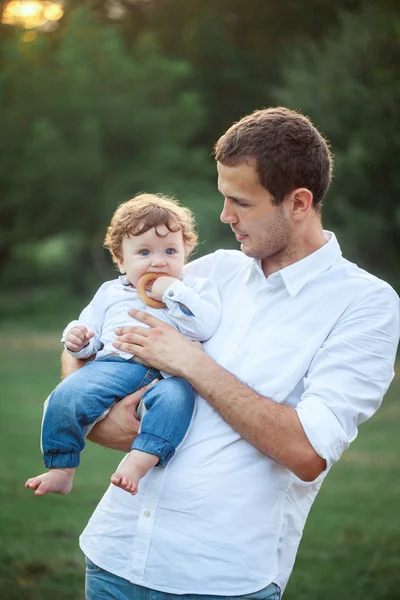 Young beautiful father and little toddler son against green grass — Stock Photo, Image