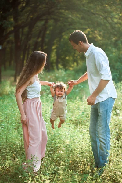 Jovem pai bonito, mãe e pequeno filho criança contra árvores verdes — Fotografia de Stock