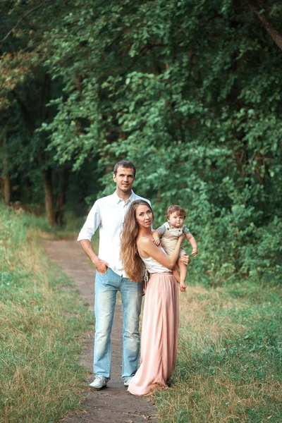 Jovem pai bonito, mãe e pequeno filho criança contra árvores verdes — Fotografia de Stock