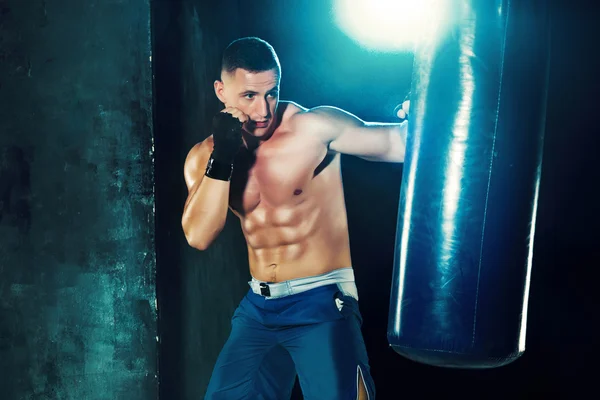 Boxeo boxeador masculino en saco de boxeo con iluminación dramática y vanguardista en un estudio oscuro —  Fotos de Stock