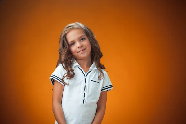 Мила весела маленька дівчинка на помаранчевому фоні — стокове фото