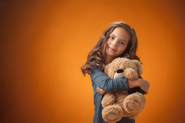 Das süße fröhliche kleine Mädchen auf orangefarbenem Hintergrund — Stockfoto