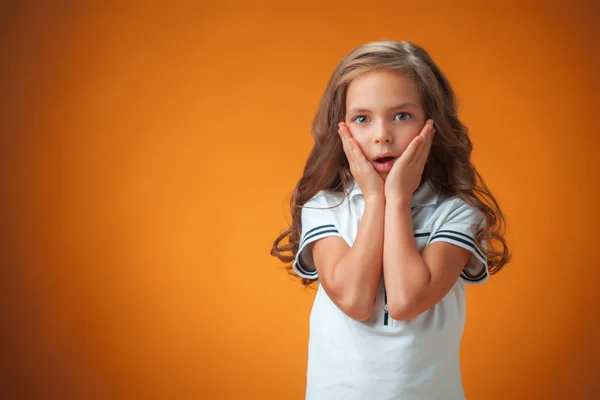 The cute surprised little girl on orange background — Stockfoto