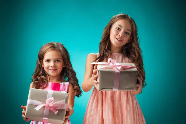 Die beiden niedlichen fröhlichen kleinen Mädchen auf blauem Hintergrund — Stockfoto
