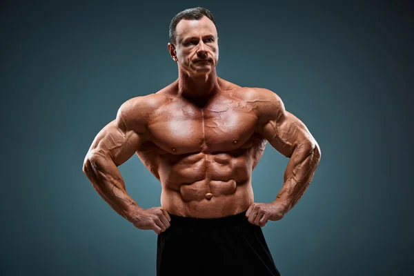 Oberkörper eines attraktiven männlichen Bodybuilders auf grauem Hintergrund. — Stockfoto