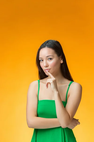 La chica china pensante sobre fondo amarillo —  Fotos de Stock