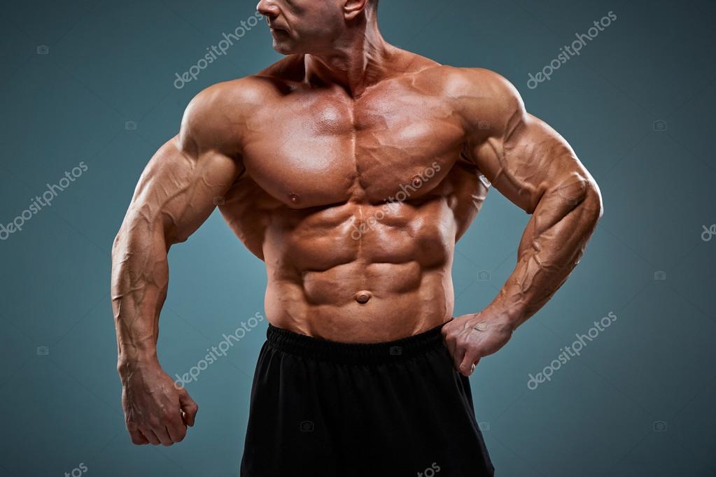 Torso of attractive male body builder on gray background. Stock Photo