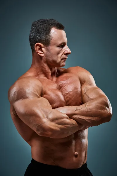 Romp van een aantrekkelijk mannelijk lichaam bouwer op grijze achtergrond. — Stockfoto