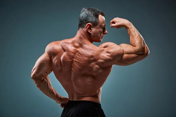 Oberkörper eines attraktiven männlichen Bodybuilders auf grauem Hintergrund. — Stockfoto