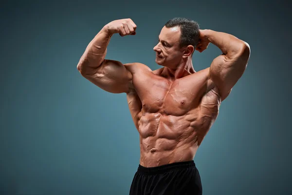 Torso of attractive male body builder on gray background. — Stock Photo, Image