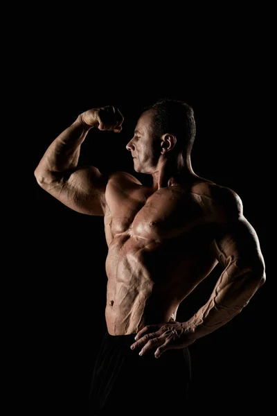 Romp van een aantrekkelijk mannelijk lichaam bouwer op zwarte achtergrond. — Stockfoto