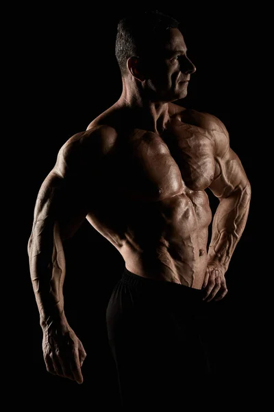 Torso de atraente construtor de corpo masculino no fundo preto . — Fotografia de Stock