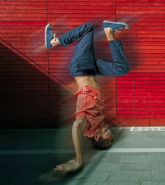 Break dançarina fazendo suporte de mão contra fundo de parede colorido — Fotografia de Stock
