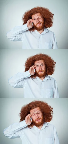 Portrét zmatený muž mluví po telefonu na šedém pozadí — Stock fotografie