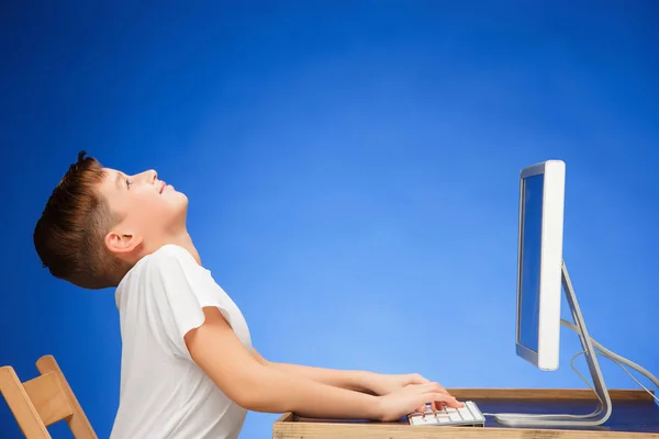 Ragazzo in età scolare seduto davanti al computer portatile di monitor a studio — Foto Stock