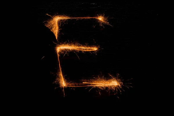 Letter E made of sparklers on black — Stock Photo, Image