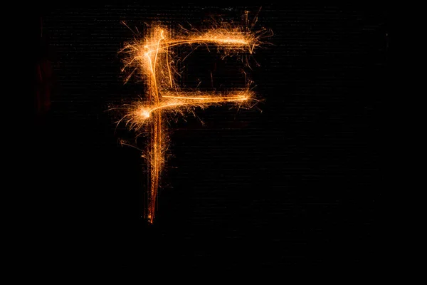 Буква F из бенгальских огней на черном — стоковое фото