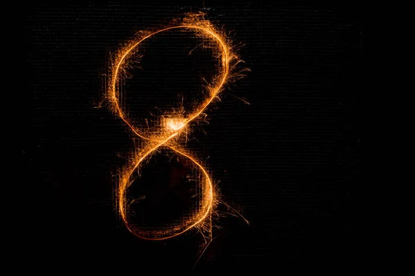 Number 8 made of sparklers on black — Stock Photo, Image